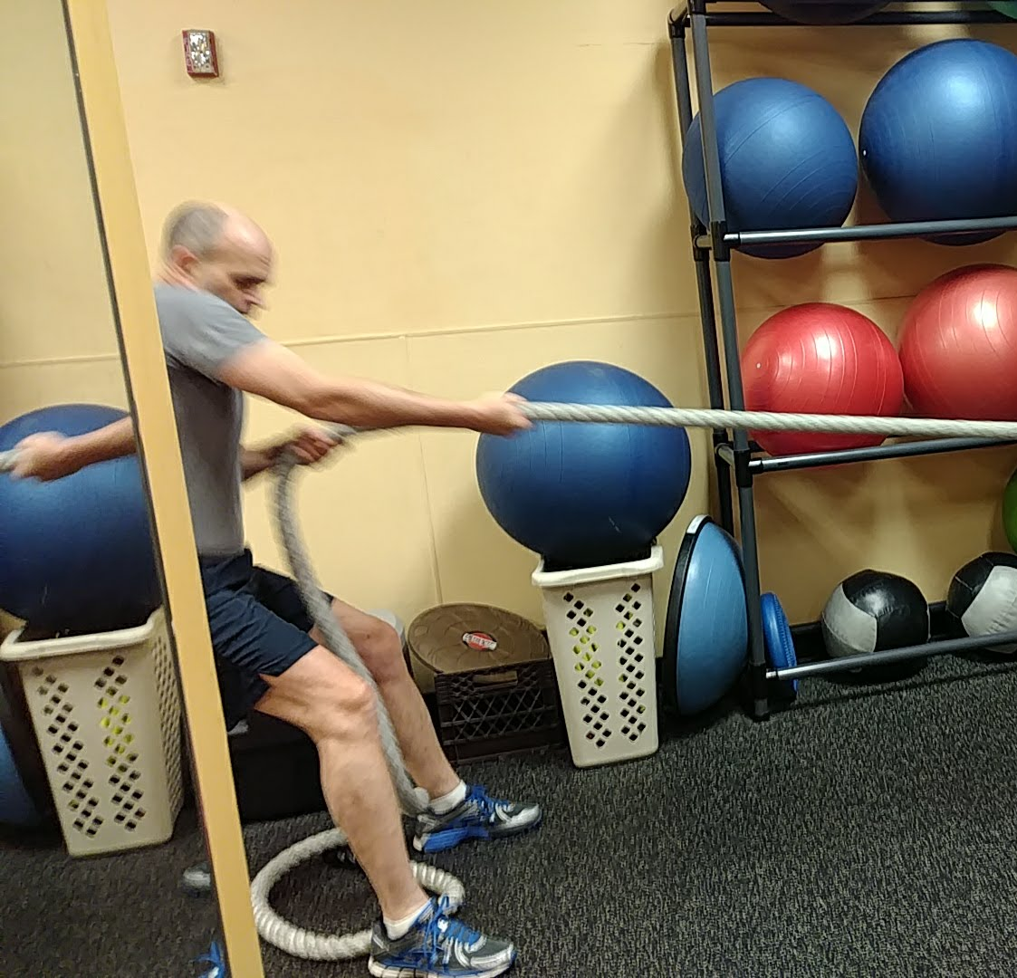 A man is pulling a rope in a gym