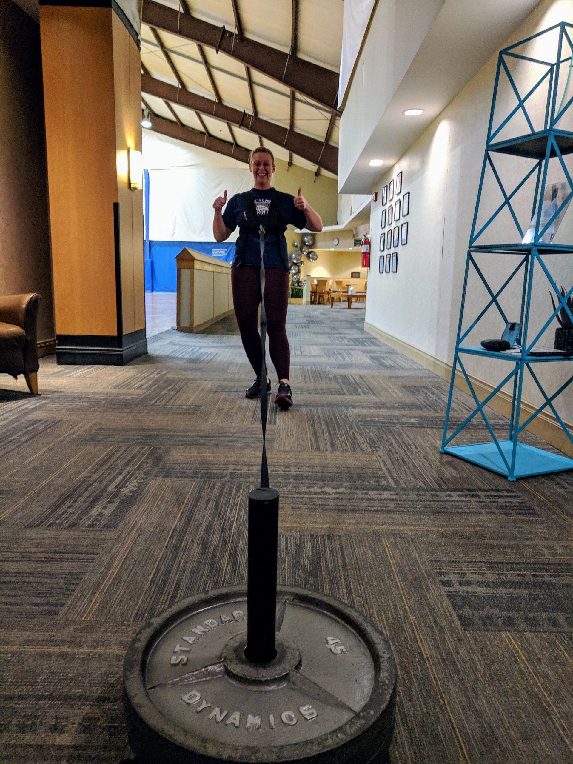A woman is standing on a barbell in a hallway