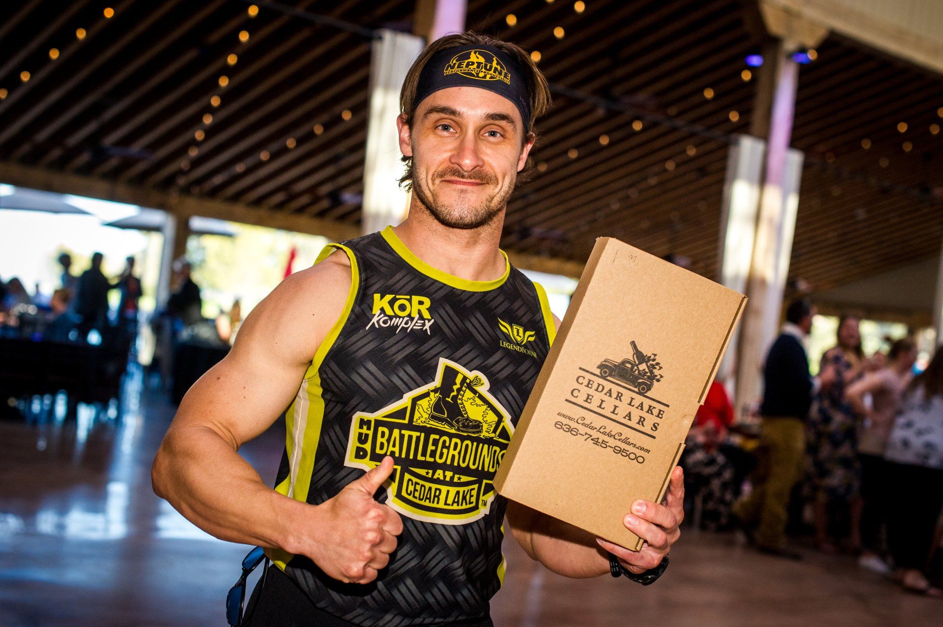 A man in a basketball jersey is holding a box and giving a thumbs up.