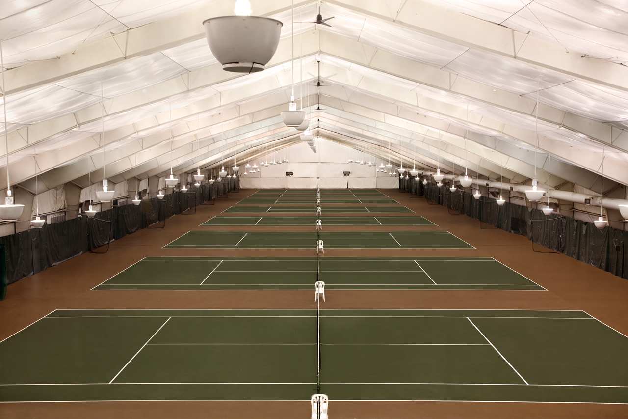 A large indoor tennis court with a white ceiling