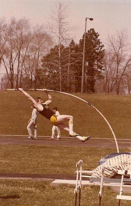 A man is jumping over a pole on a track
