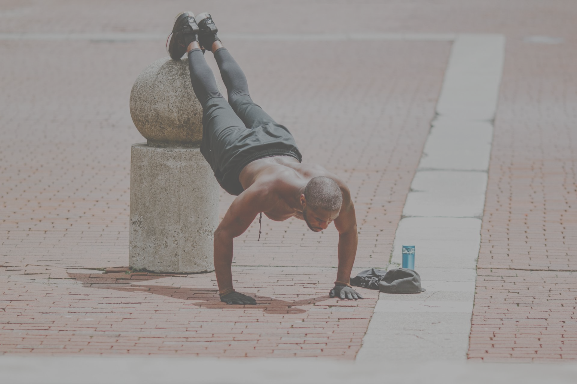 A shirtless man is doing push ups on the sidewalk.