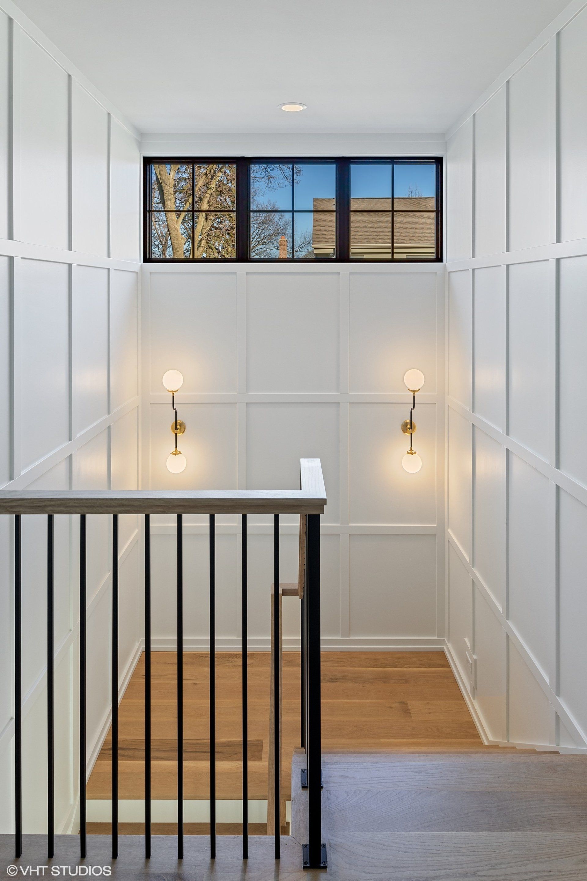 A staircase with white paneling and a window