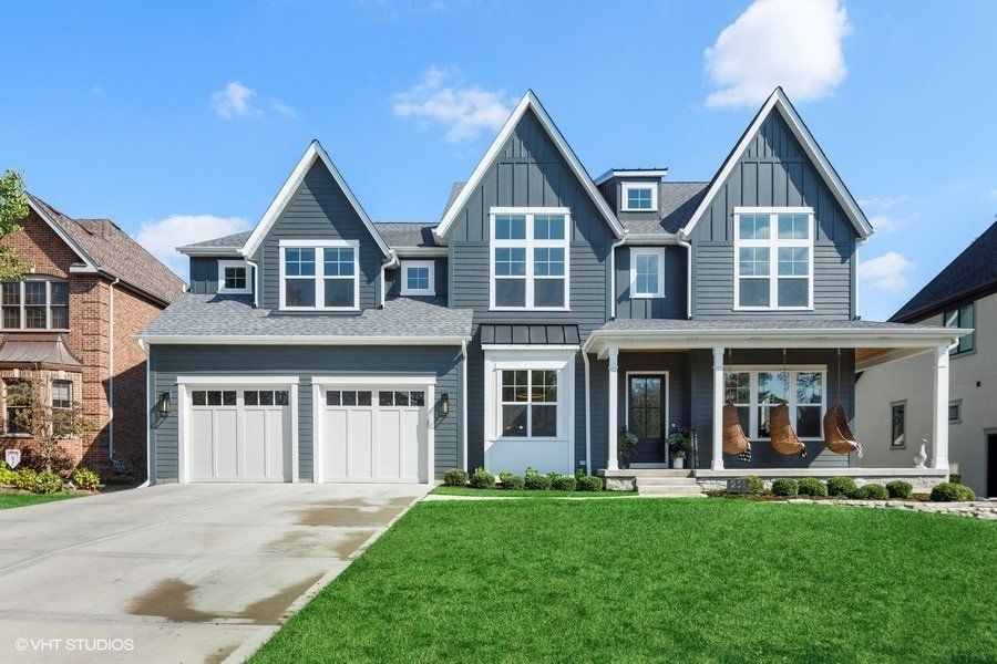 A large gray house with white garage doors and a porch