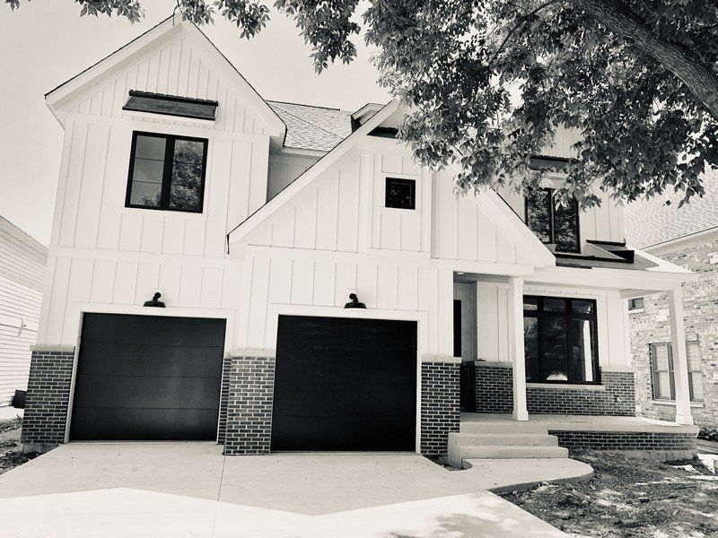 A black and white photo of a house with two garage doors.