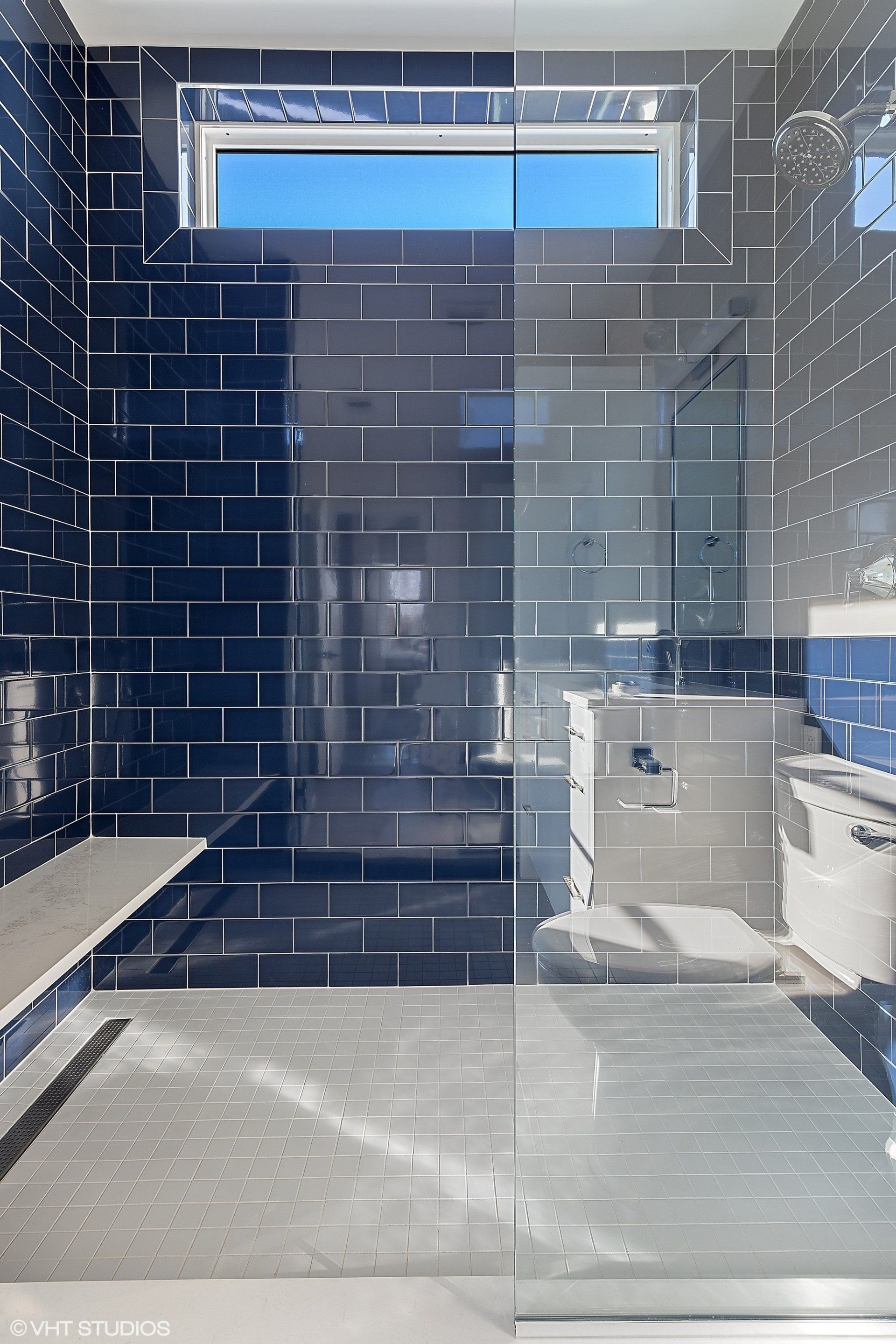 A bathroom with black tiles and a walk in shower