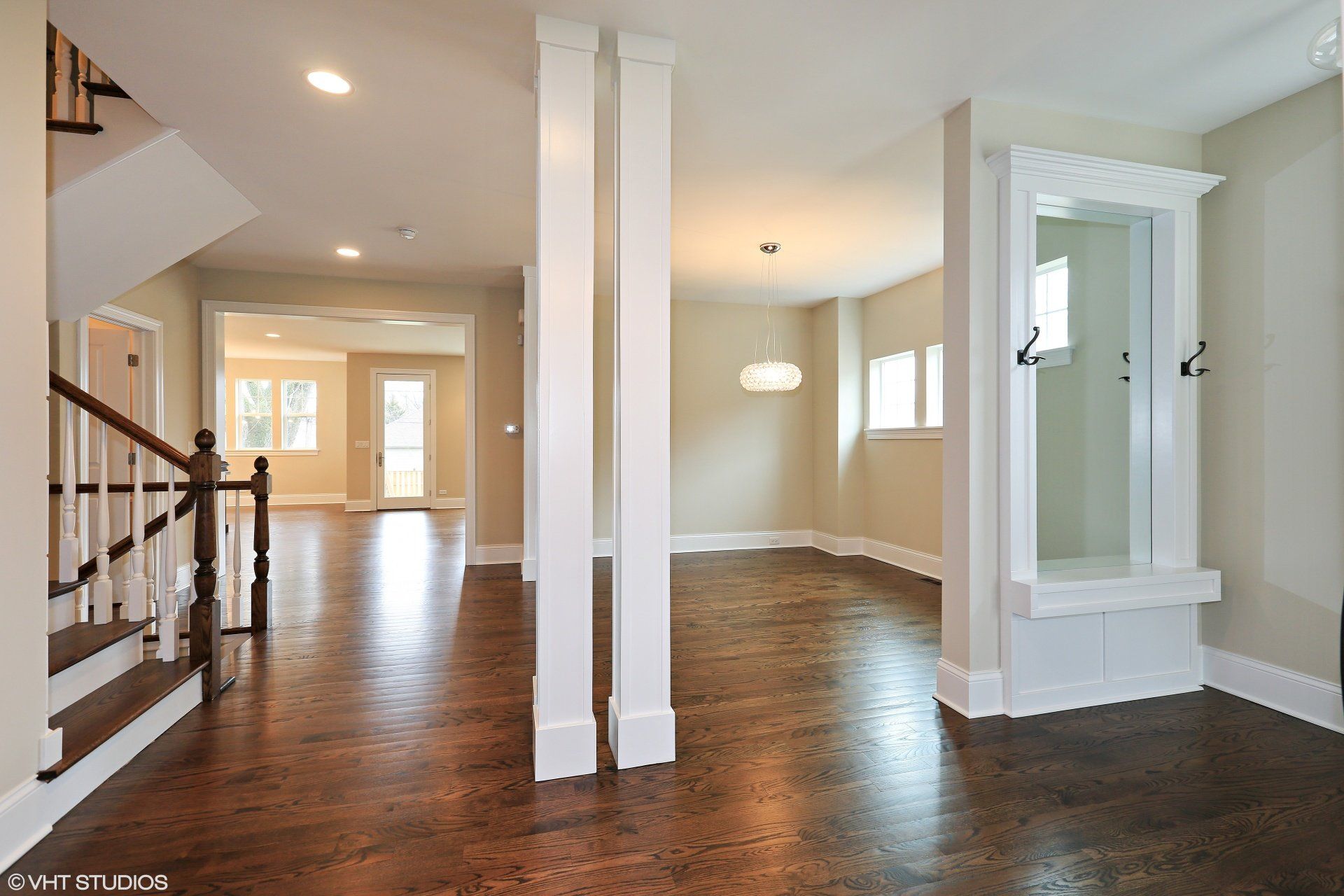 A large empty room with hardwood floors and white pillars