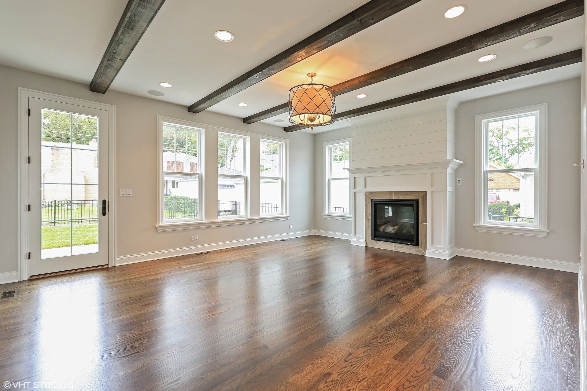 An empty living room with hardwood floors and a fireplace.