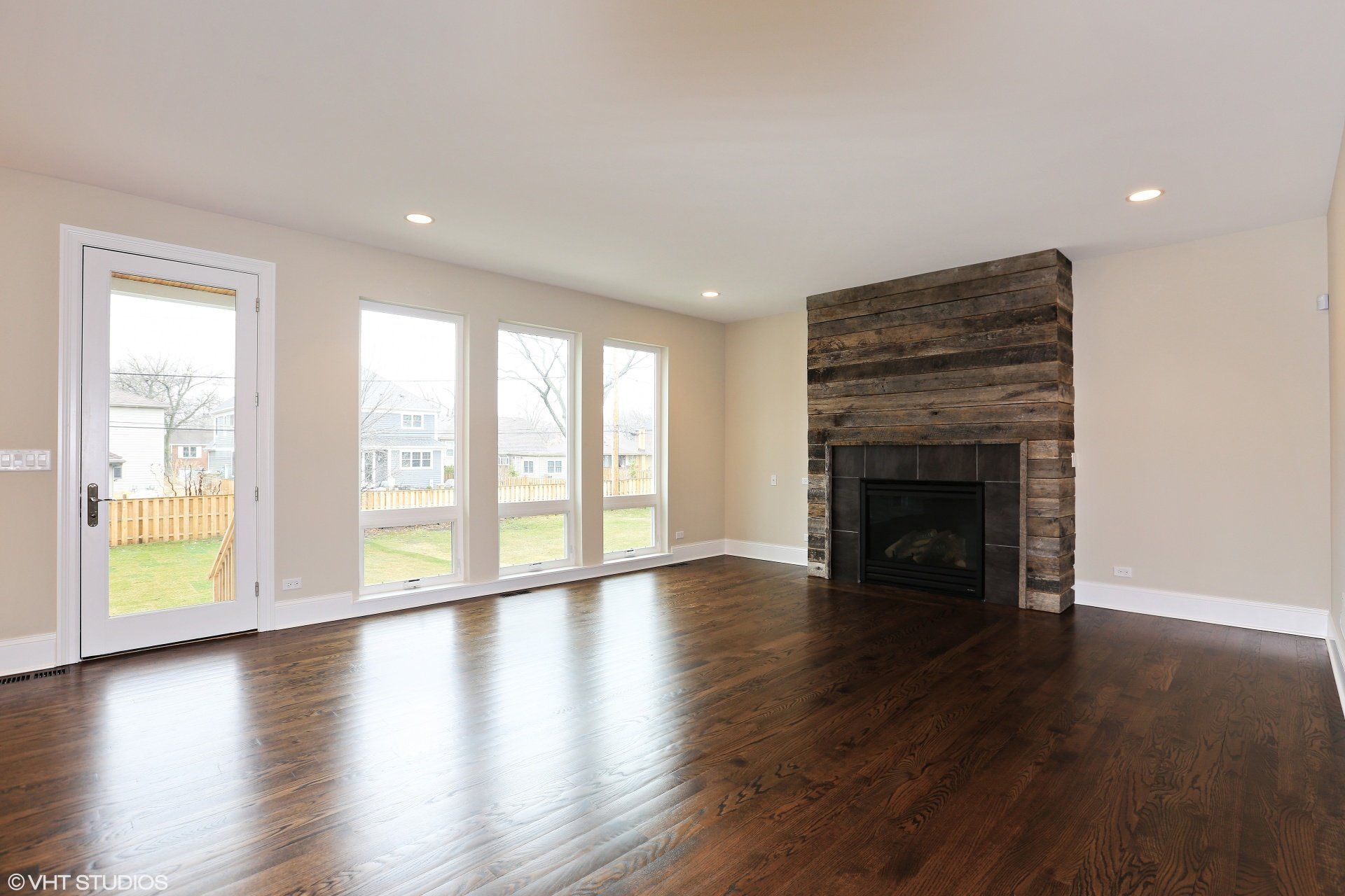 An empty living room with hardwood floors and a fireplace.