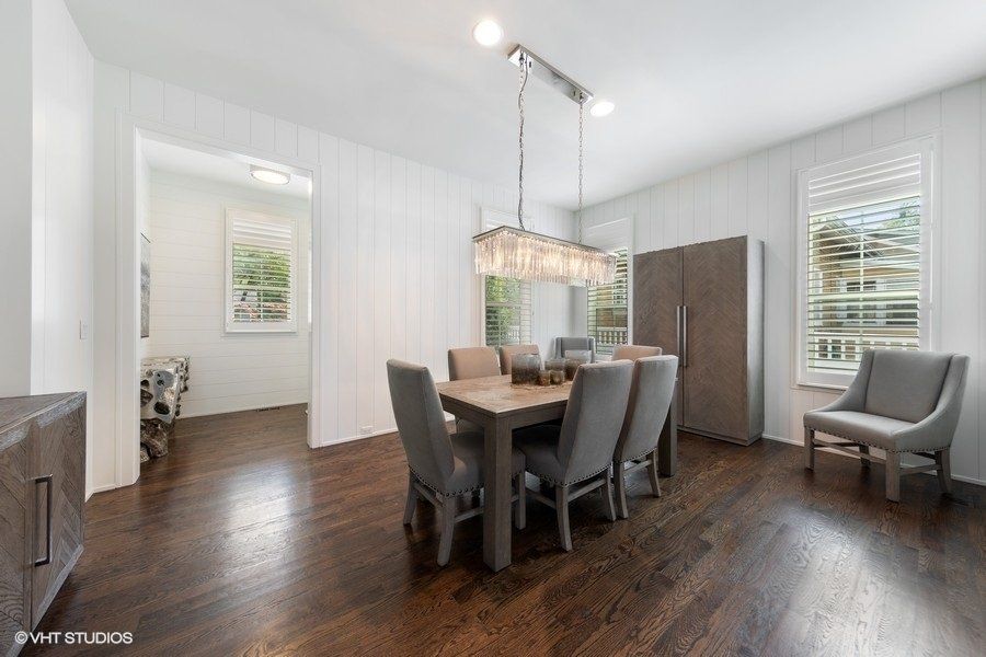 A dining room with a table and chairs and a refrigerator.