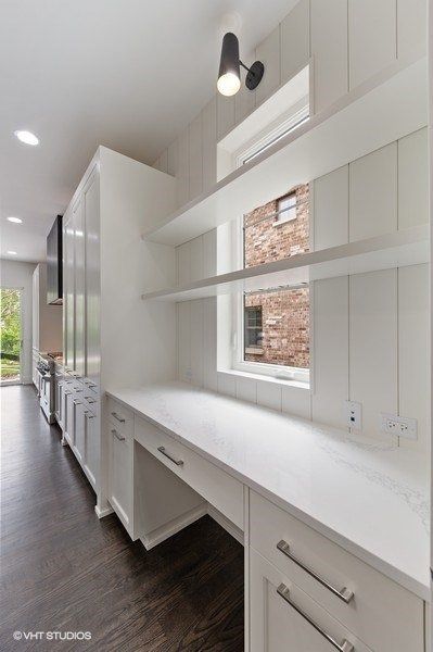 A white desk with a window and shelves in a kitchen