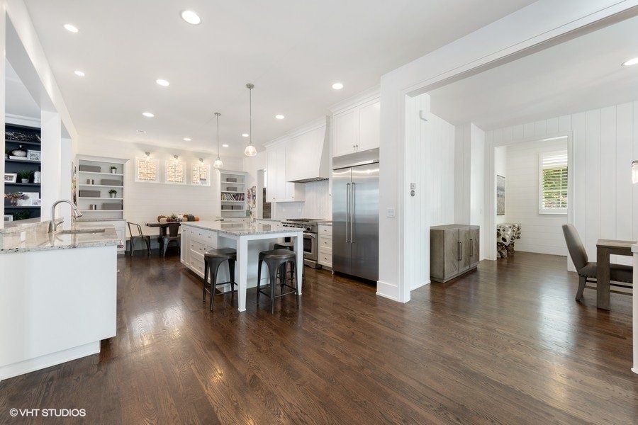 A kitchen with white cabinets and stainless steel appliances and hardwood floors.