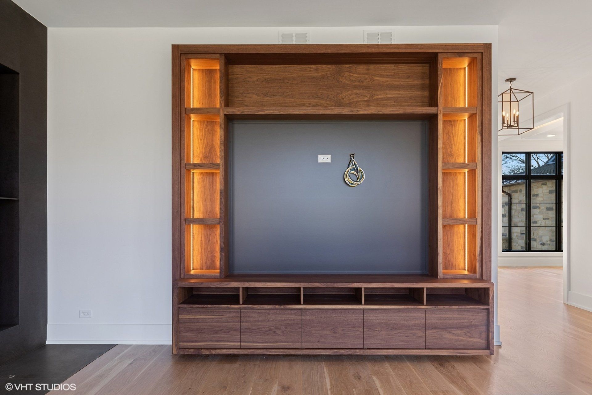 A wooden entertainment center in a living room with lights on the shelves