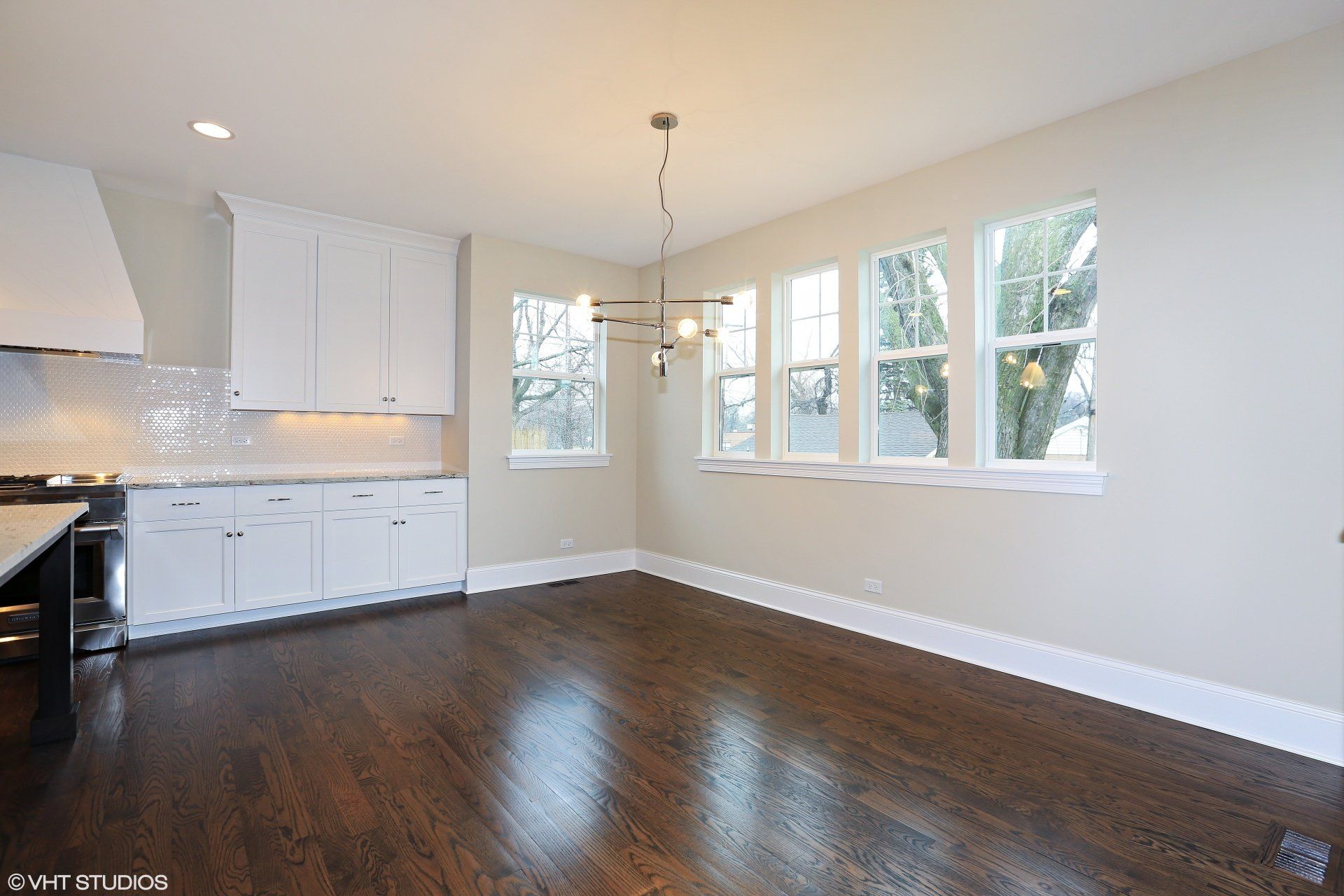An empty kitchen with hardwood floors and white cabinets