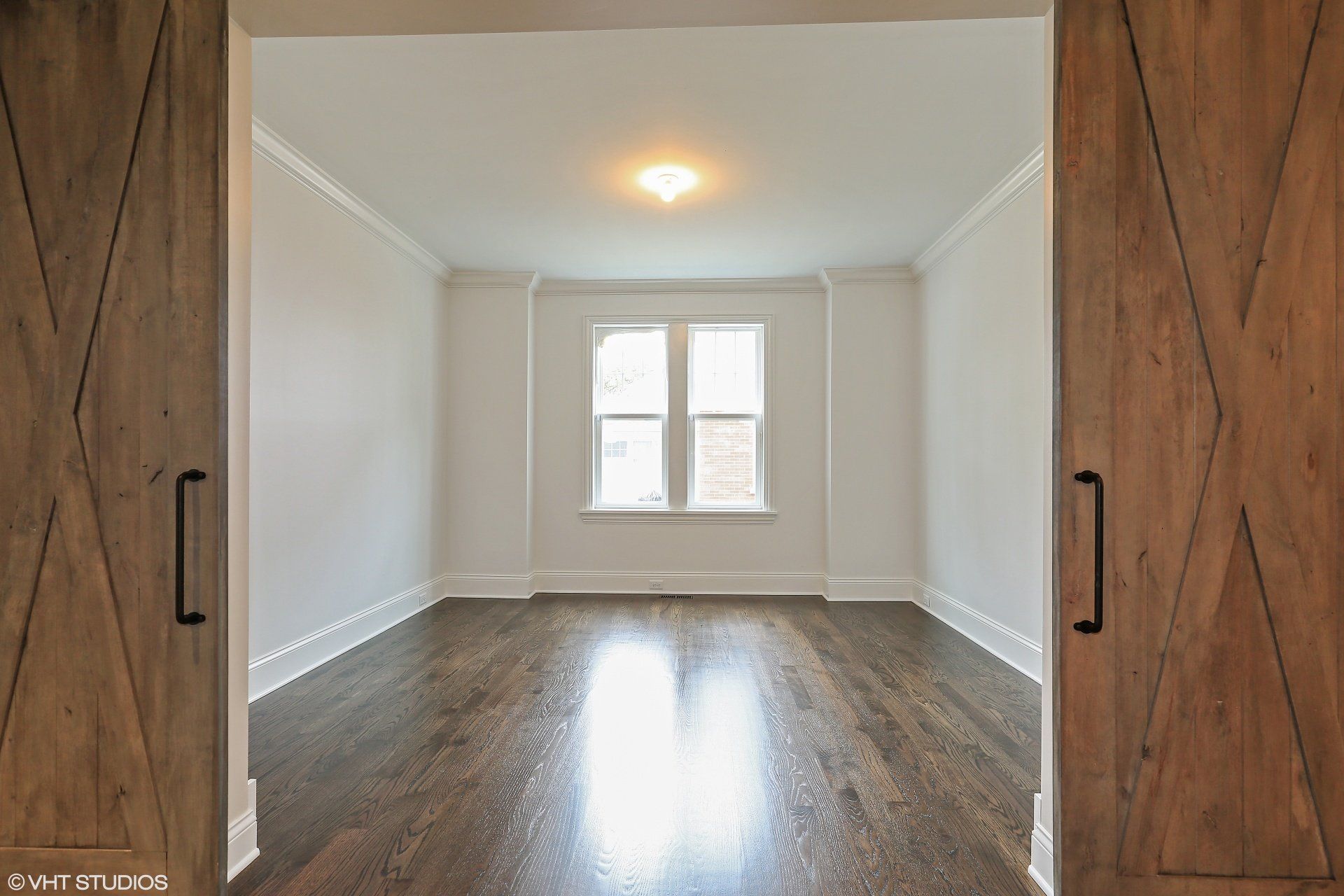An empty room with hardwood floors and sliding barn doors.