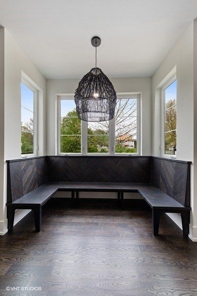 There is a bench in the middle of the room with a chandelier hanging from the ceiling.