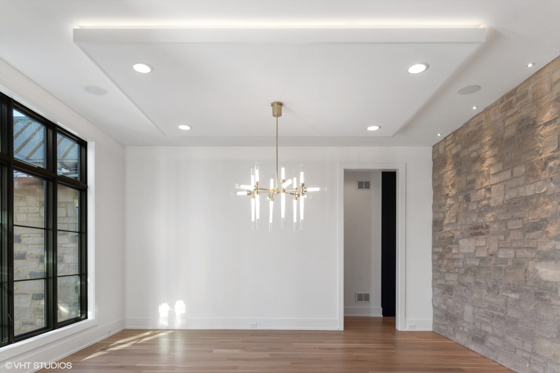 An empty room with a chandelier hanging from the ceiling and a brick wall.