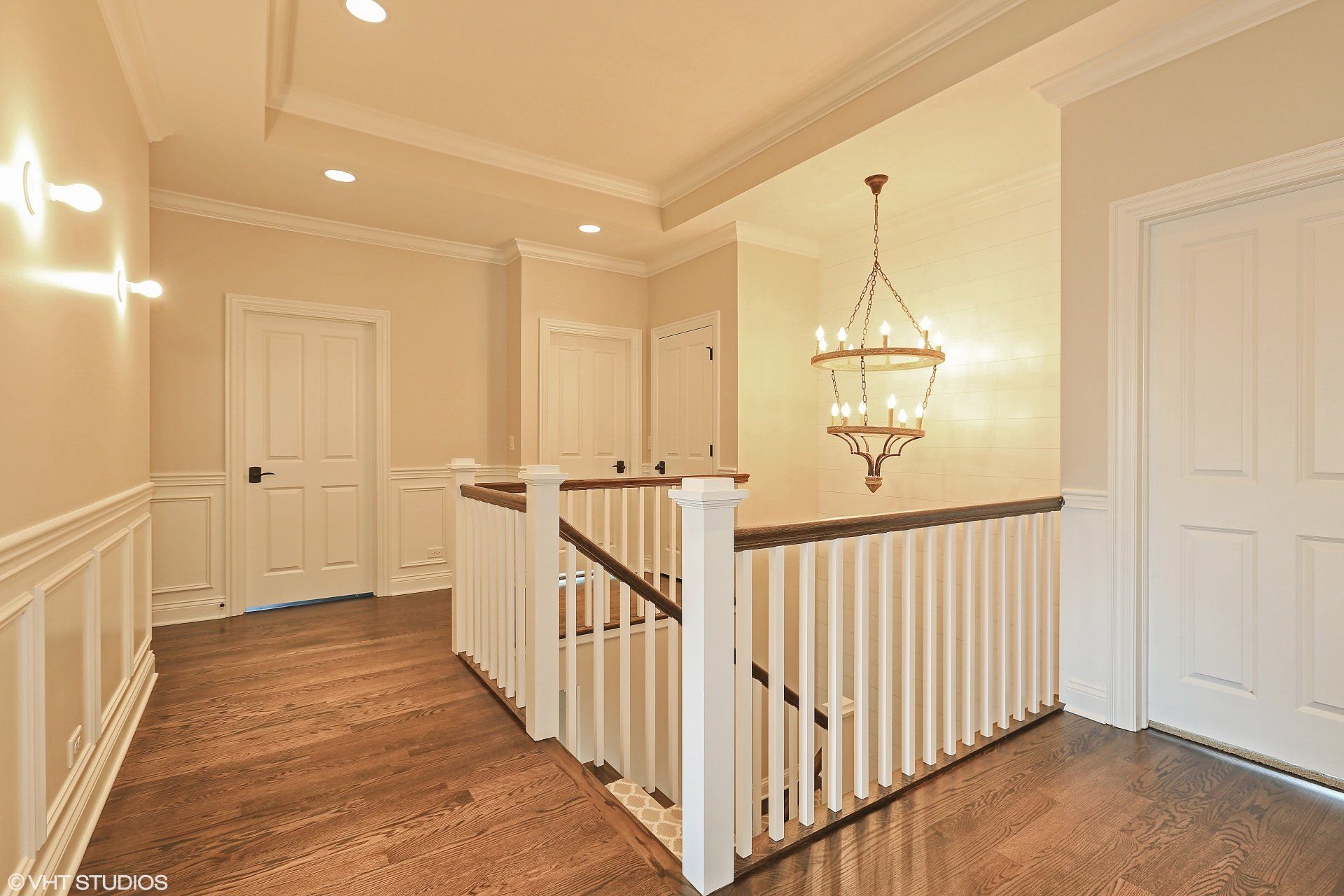 A hallway with a staircase and a chandelier hanging from the ceiling.