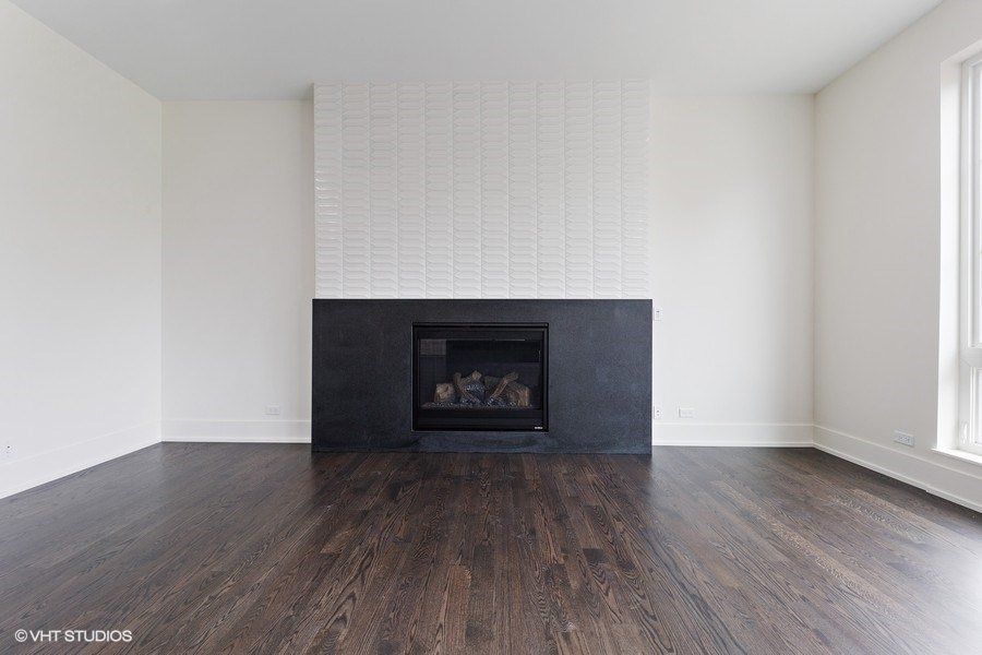 An empty living room with a fireplace and hardwood floors