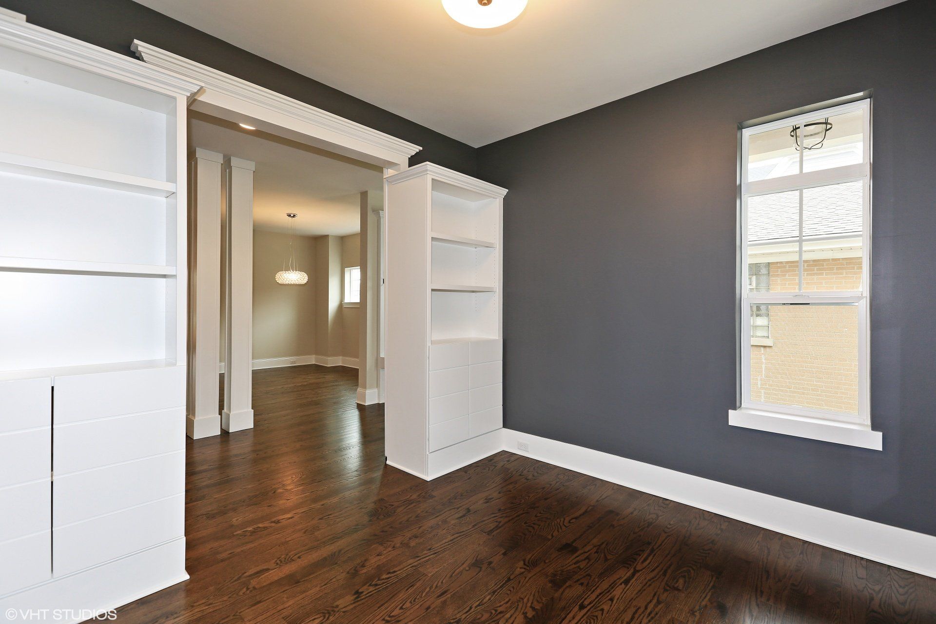 An empty room with dark wood floors and gray walls