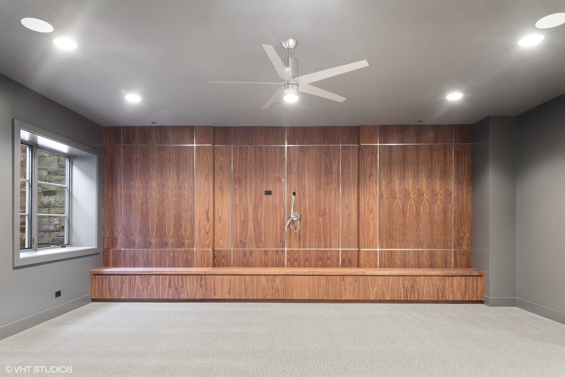 An empty room with a wooden wall and a ceiling fan