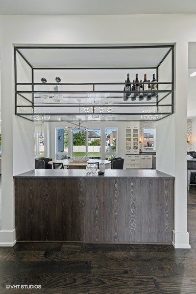 A kitchen with a bar and a wine rack above it