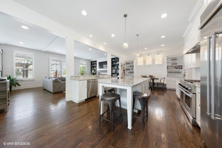 A kitchen with hardwood floors , stainless steel appliances and a large island.