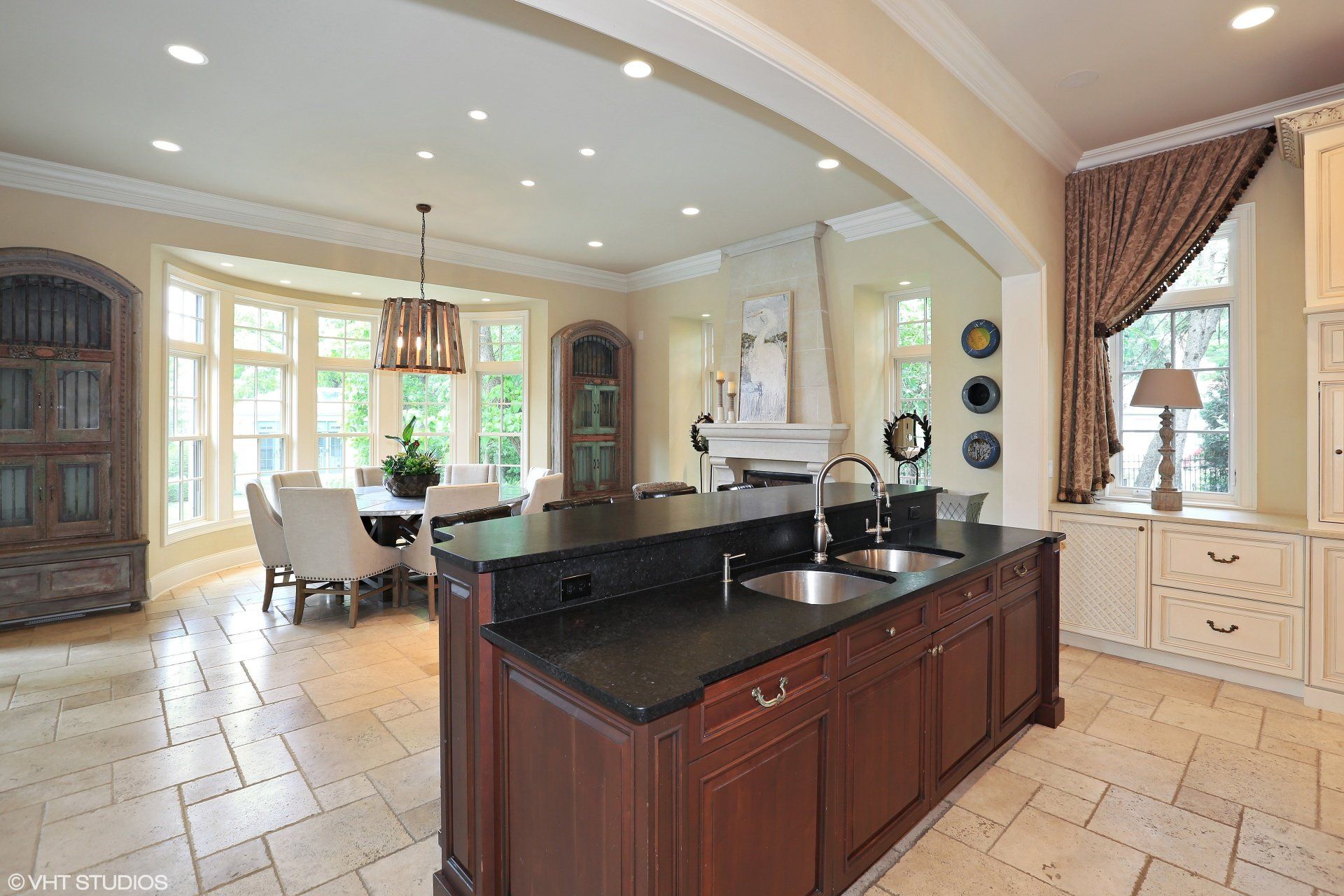 A kitchen with a large island and a sink and a dining room in the background.