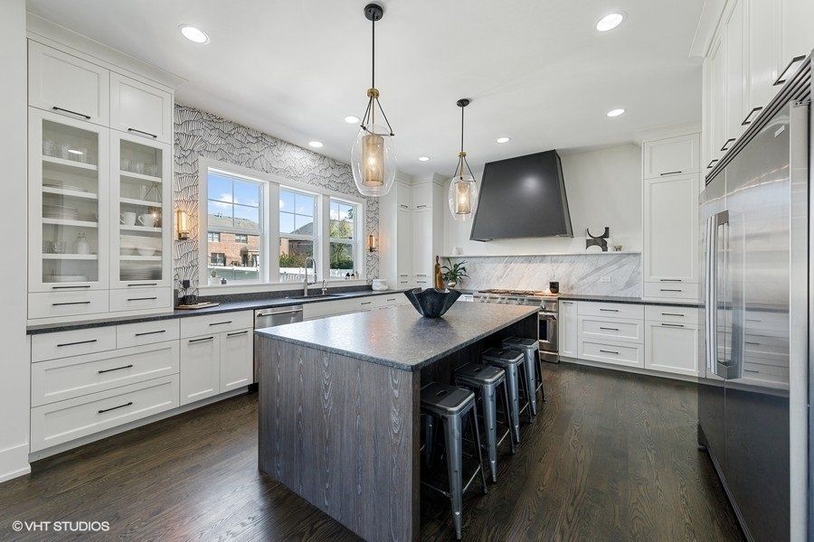 A kitchen with white cabinets and stainless steel appliances and a large island.
