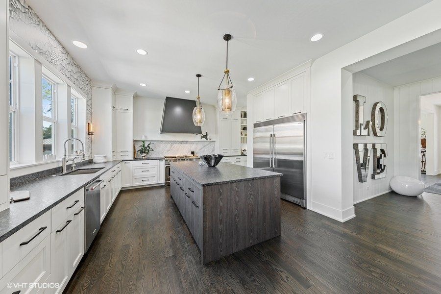 A kitchen with white cabinets , stainless steel appliances , and a large island.