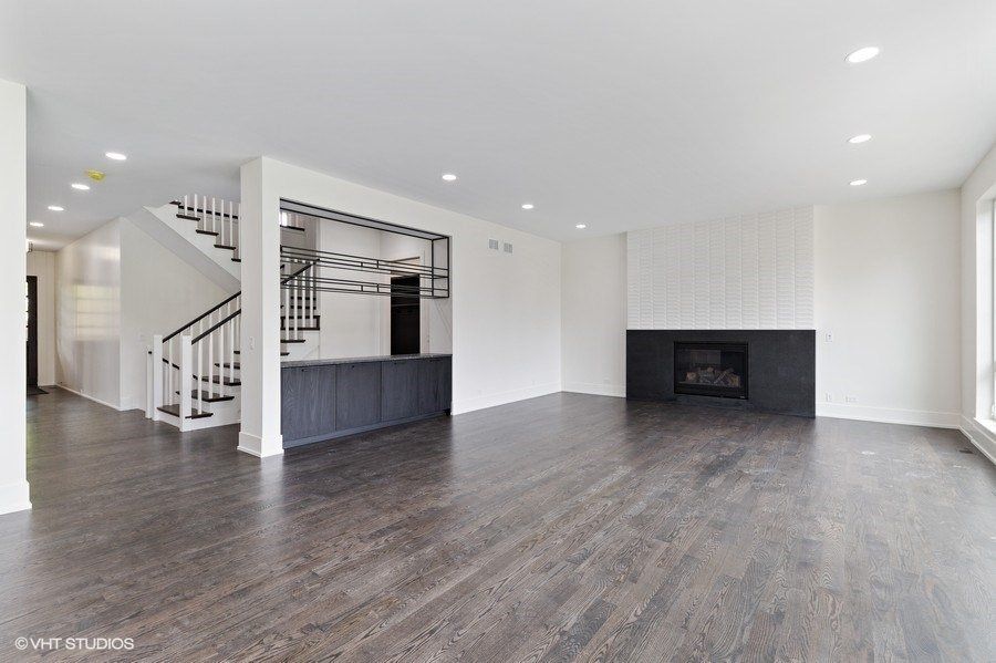 An empty living room with hardwood floors and a fireplace.