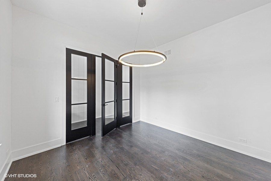 An empty room with black doors and a light hanging from the ceiling.