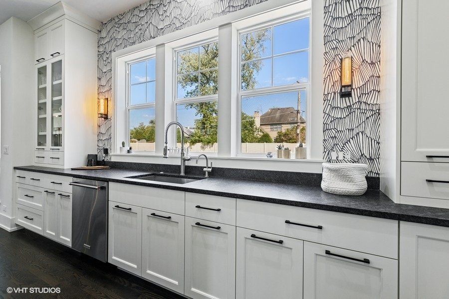 A kitchen with white cabinets , black counter tops , and a sink.