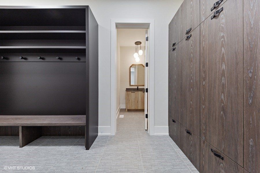 A walk in closet with wooden cabinets and a bench.