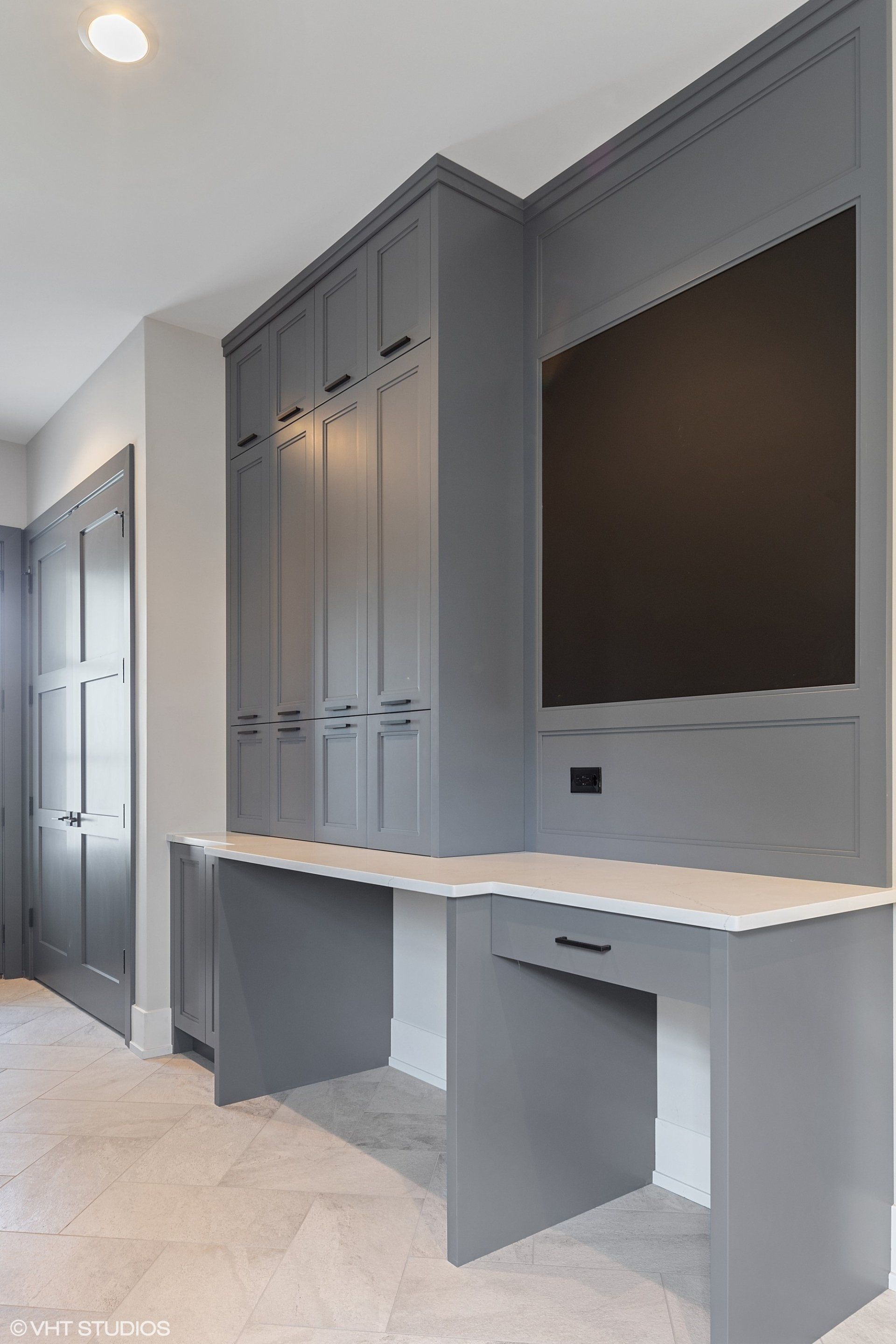 A room with a desk and a television on the wall.