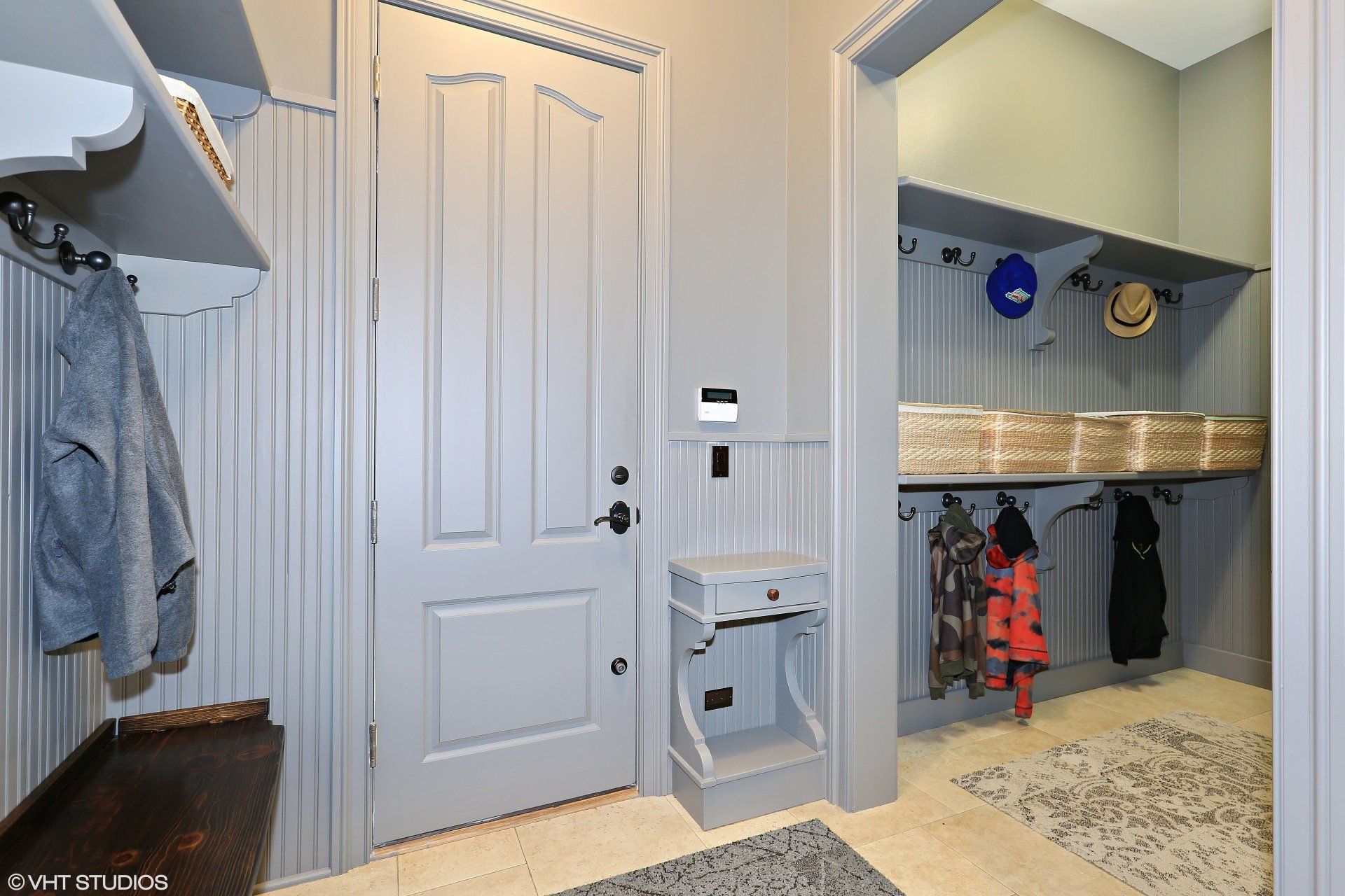 A hallway with a door and a shelf with clothes hanging on it.