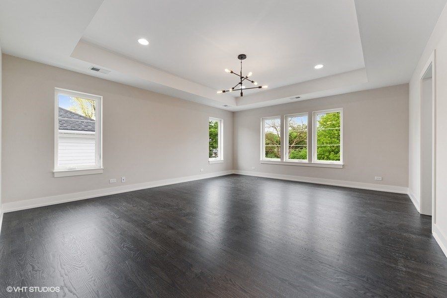An empty living room with hardwood floors and a chandelier.
