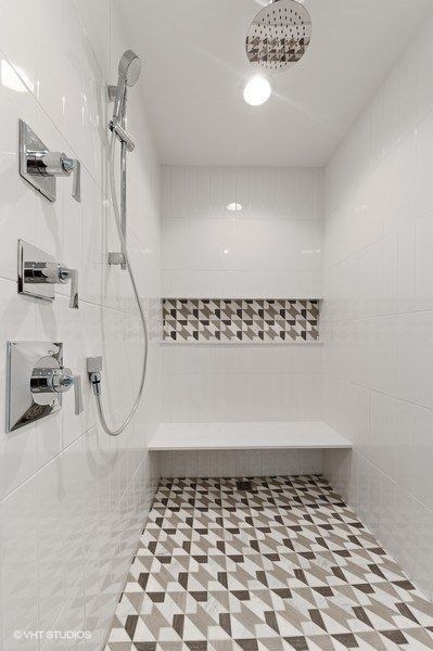 A shower with a bench and a shower head.