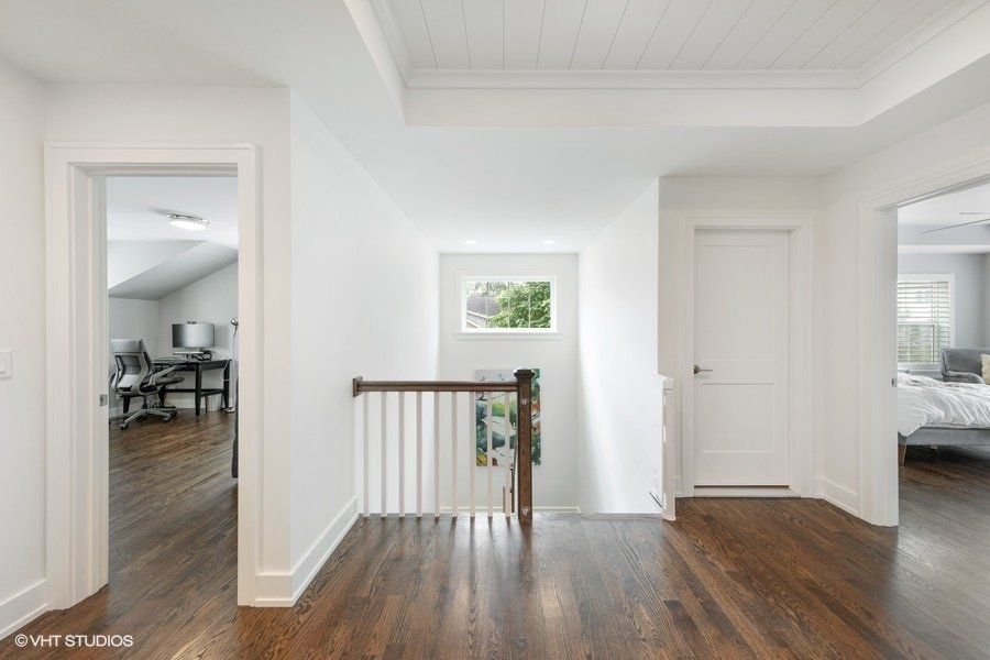 A hallway in a house with hardwood floors and white walls.