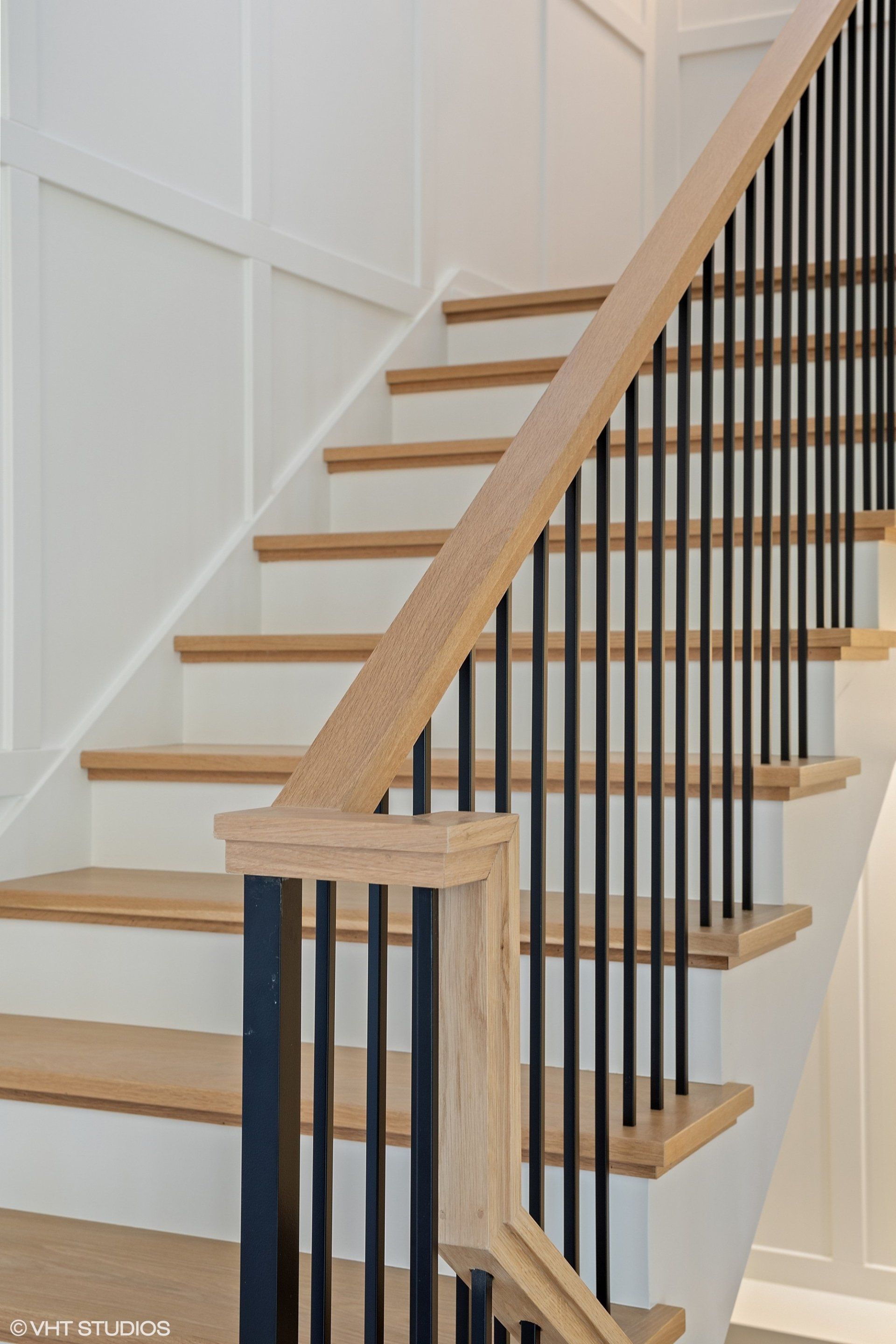 A close up of a wooden staircase with a black railing.