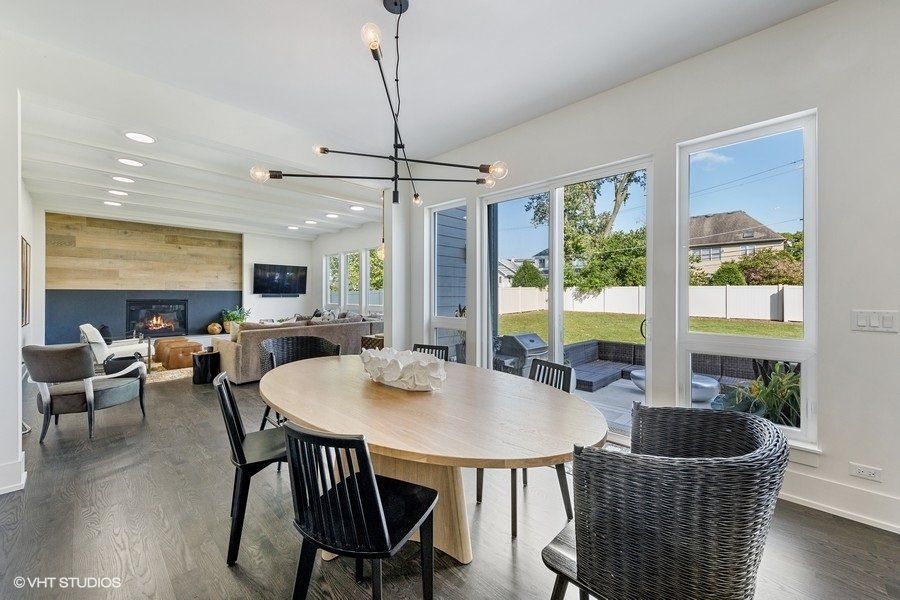 A dining room with a round table and chairs and a chandelier hanging from the ceiling.