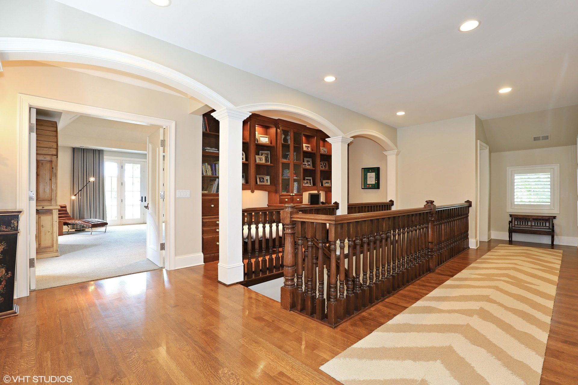 A hallway in a house with a staircase and a rug