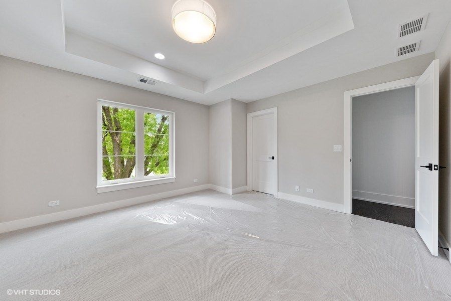 An empty bedroom with a ceiling fan and two windows.