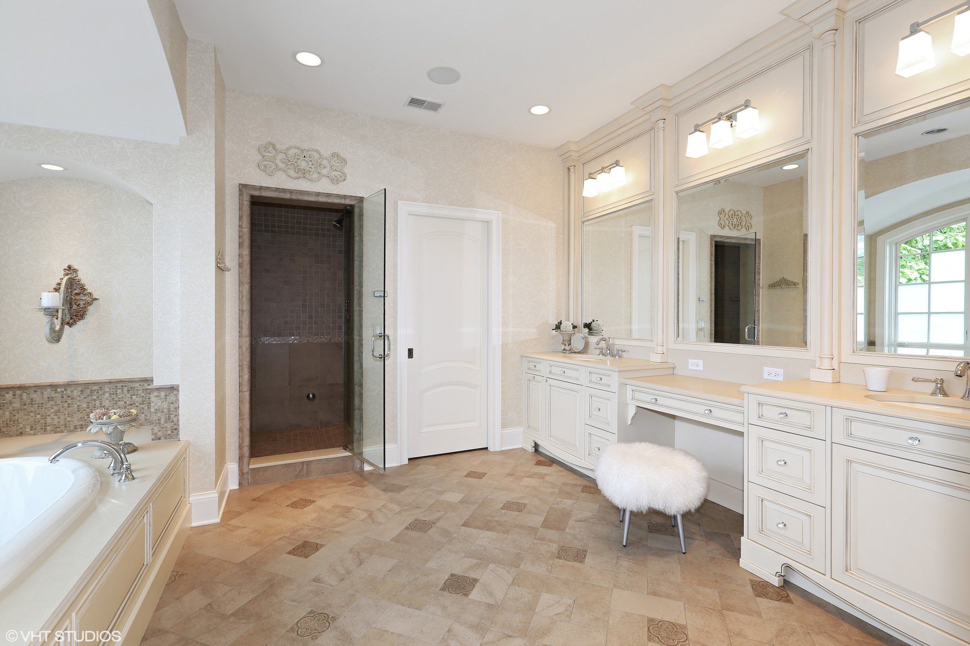 A bathroom with white cabinets and mirrors and a bathtub