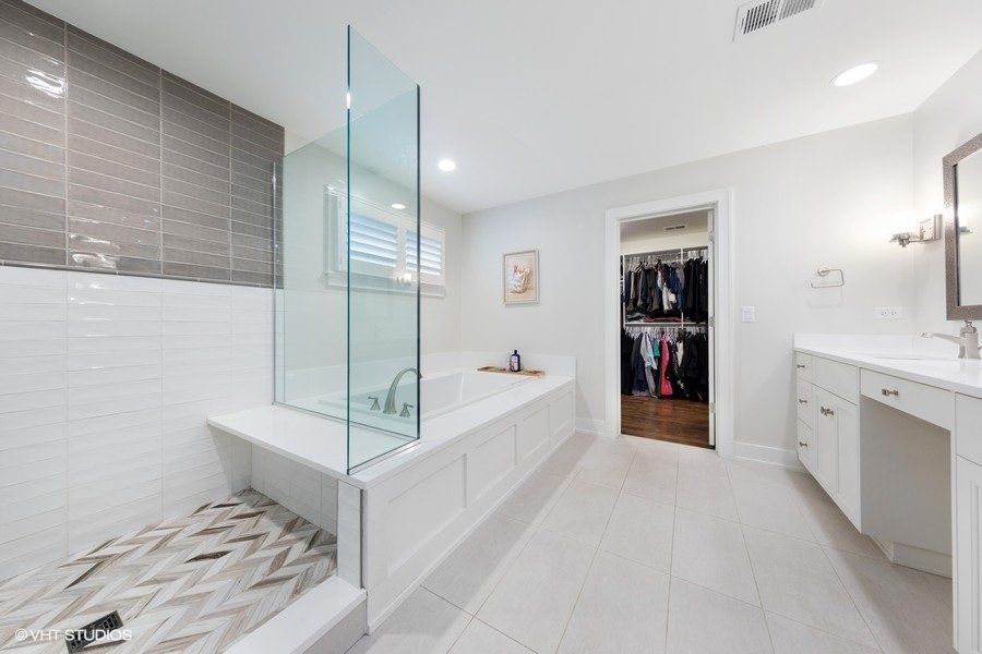 A bathroom with a walk in shower , tub , sink and mirror.