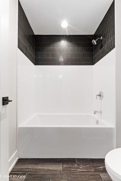 A bathroom with a bathtub , toilet and shower.
