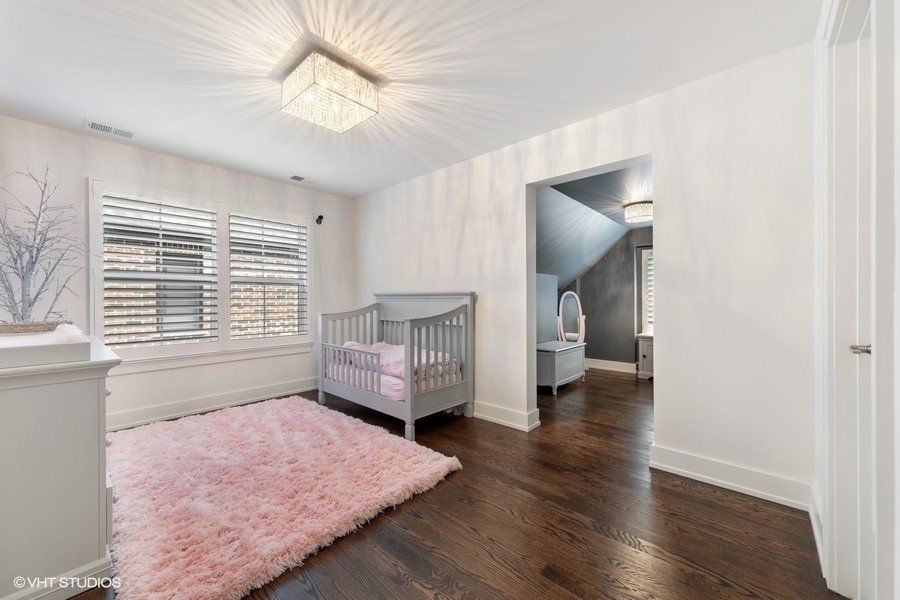 A bedroom with a crib and a pink rug.