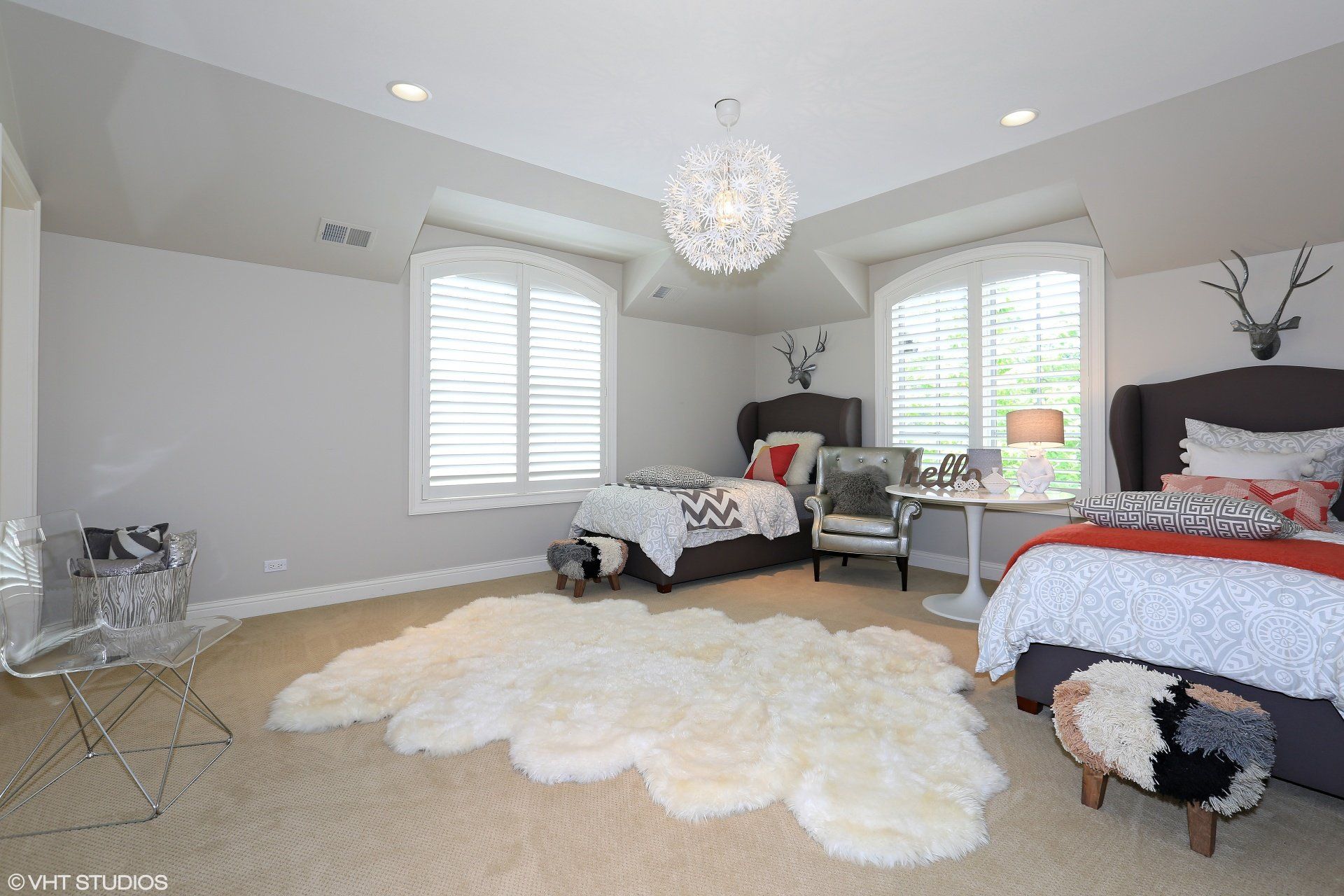 A bedroom with two beds , a chair , a rug and a chandelier.