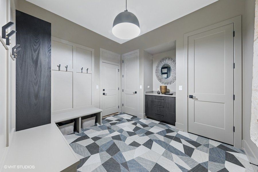 A hallway with a geometric patterned floor and a bench.