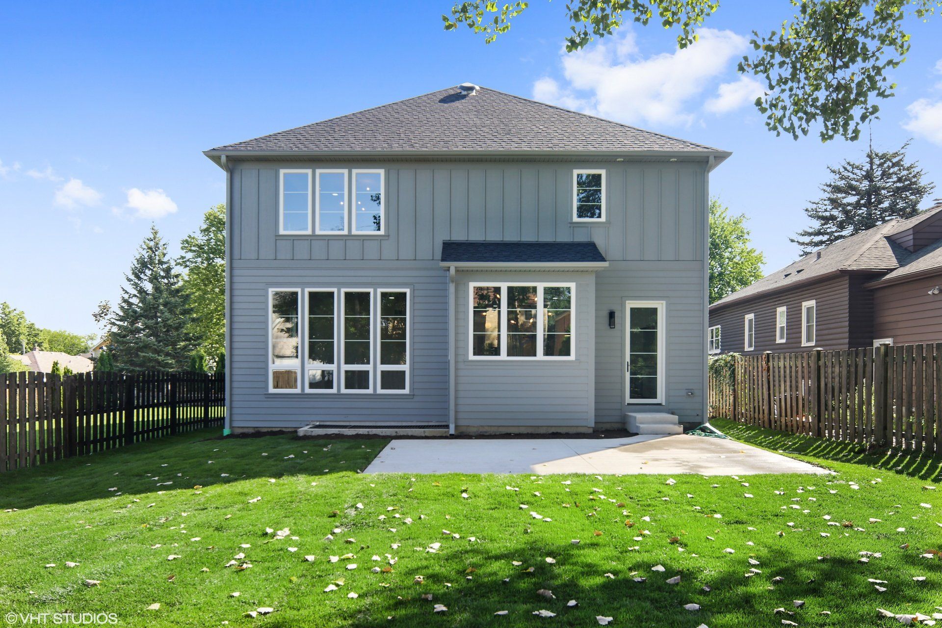 The back of a house with a lot of windows and a fence.